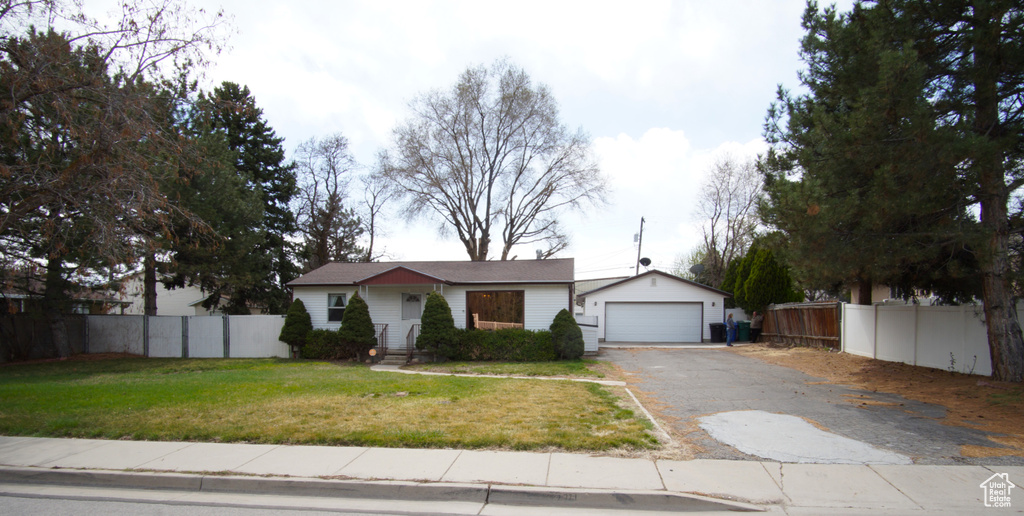 Ranch-style home with a front yard, an outdoor structure, fence, aphalt driveway, and a detached garage