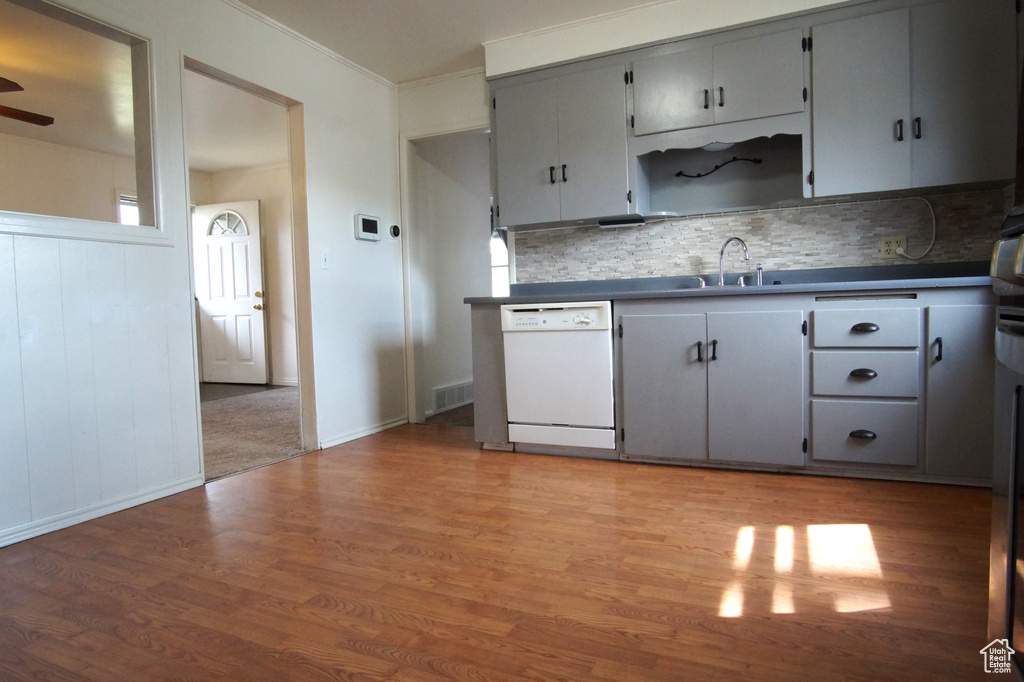 Kitchen featuring a sink, dark countertops, ceiling fan, light wood-style flooring, and white dishwasher