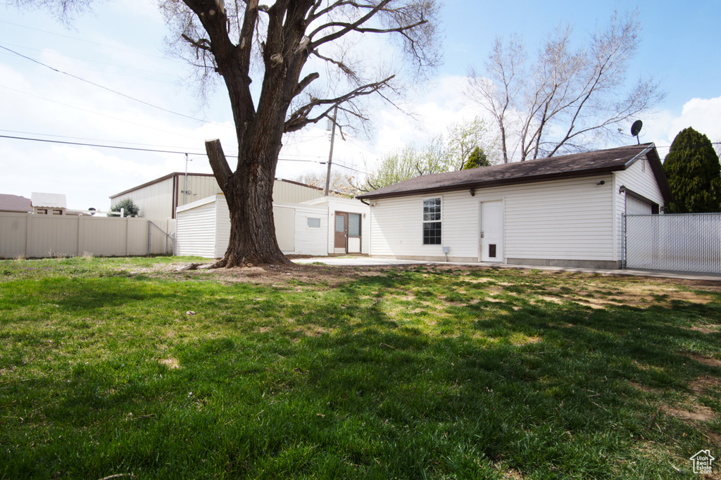 Rear view of property featuring an outbuilding, fence, and a yard