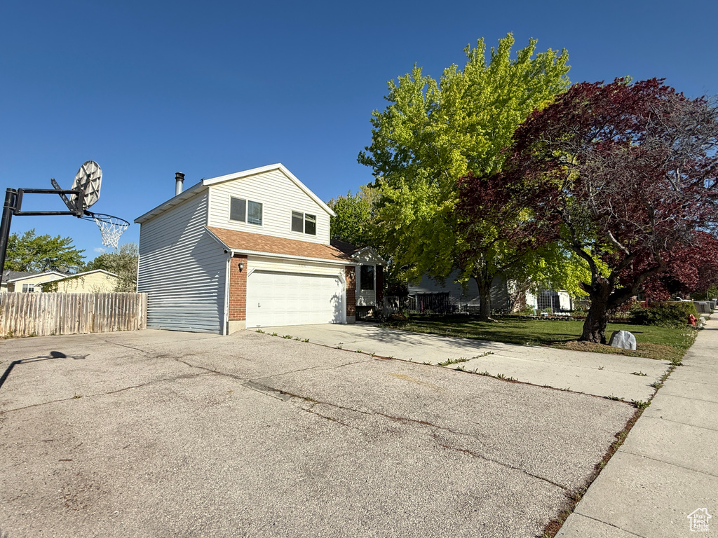 View of home's exterior with fence, an attached garage, and aphalt driveway
