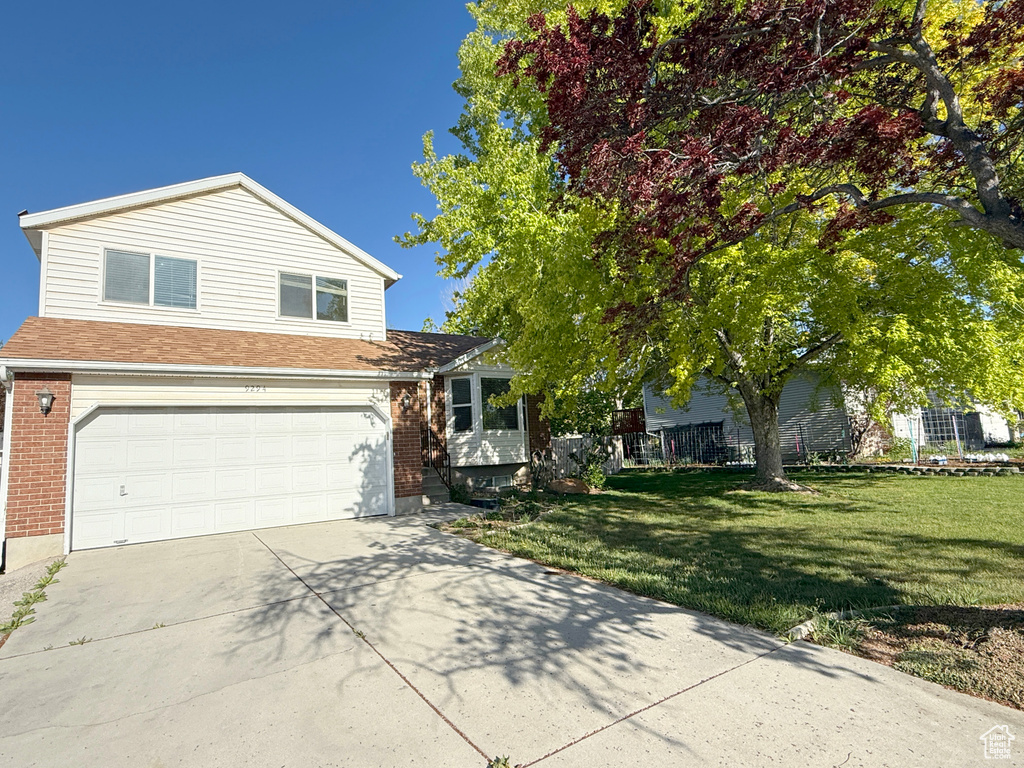 View of front facade featuring concrete driveway, brick siding, and a front yard