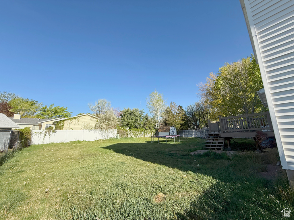 View of yard featuring stairs, a fenced backyard, a trampoline, and a wooden deck