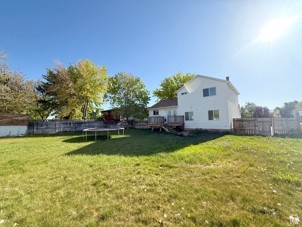 View of yard featuring a storage shed, a wooden deck, a fenced backyard, and a trampoline