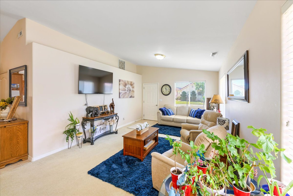 Carpeted living area with baseboards, visible vents, and lofted ceiling