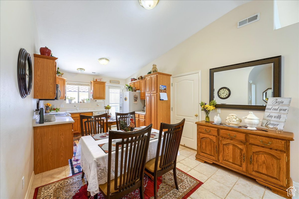 Dining room with light tile patterned floors, vaulted ceiling, and visible vents