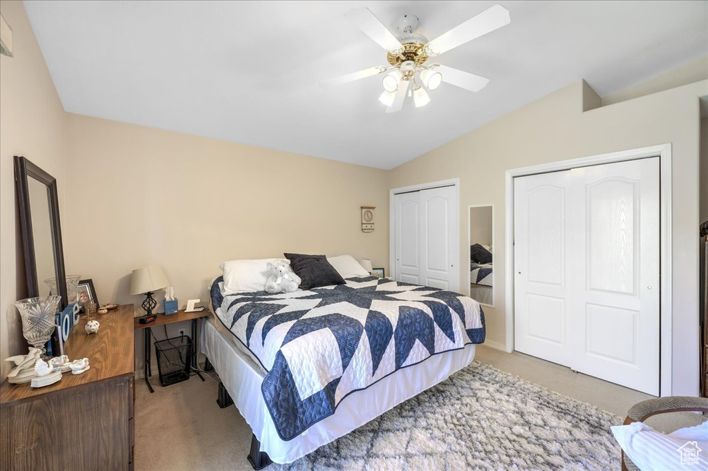 Bedroom featuring two closets, vaulted ceiling, ceiling fan, and carpet