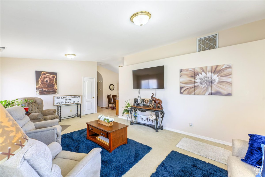 Living room featuring vaulted ceiling, carpet floors, baseboards, visible vents, and arched walkways