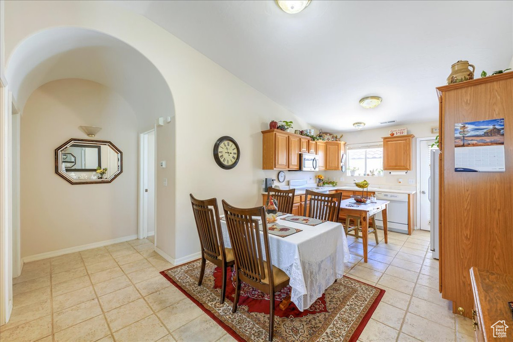 Dining area with baseboards, high vaulted ceiling, arched walkways, and light tile patterned floors