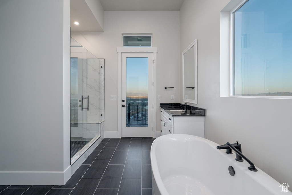 Bathroom with a stall shower, a freestanding bath, vanity, baseboards, and recessed lighting