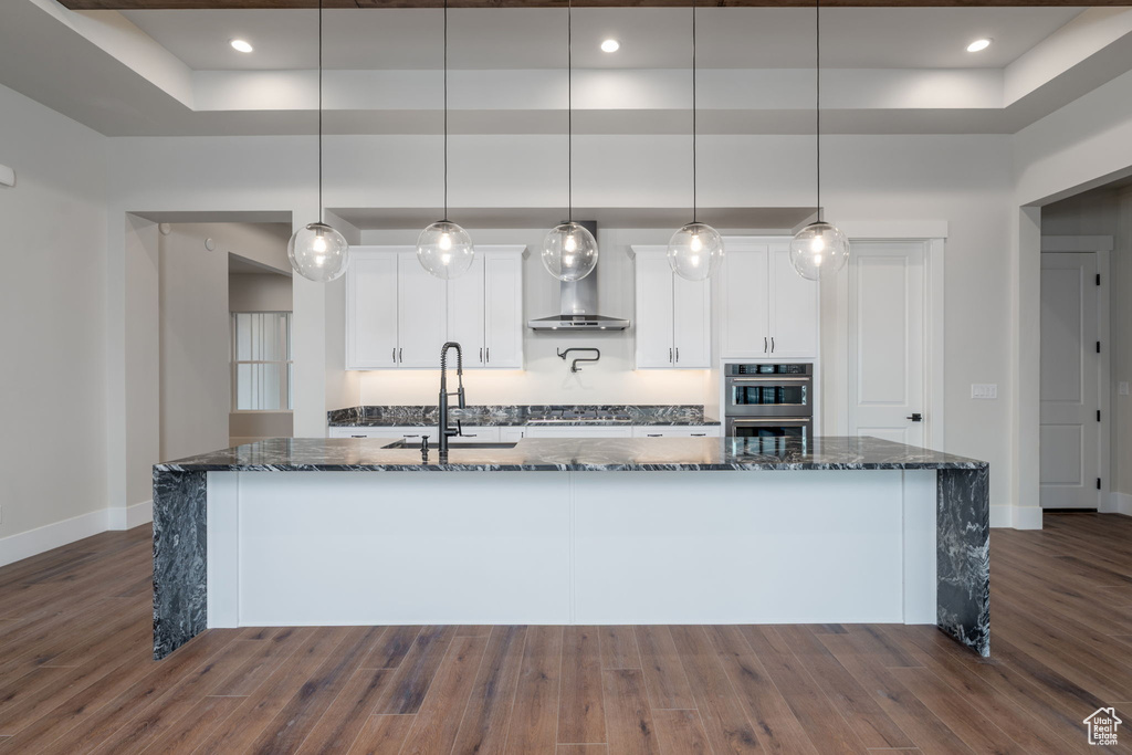 Kitchen featuring a raised ceiling, a sink, baseboards, dark wood finished floors, and white cabinets