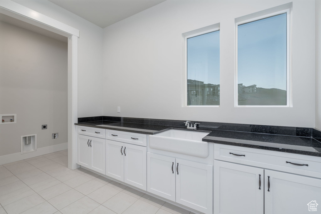 Laundry room with hookup for an electric dryer, washer hookup, cabinet space, light tile patterned flooring, and baseboards