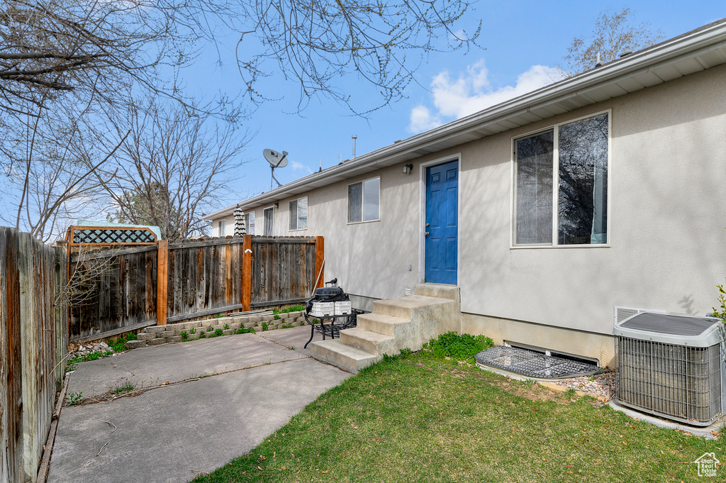 Exterior space with cooling unit, stucco siding, fence, and a patio area