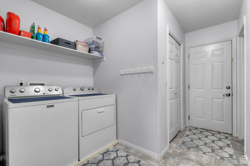 Washroom with baseboards, washing machine and clothes dryer, laundry area, and a textured ceiling