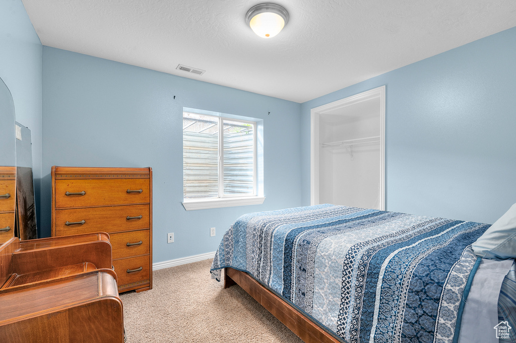 Carpeted bedroom with baseboards, visible vents, and a closet