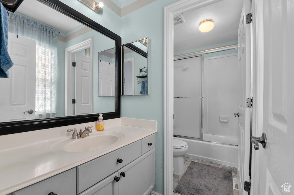 Full bath featuring enclosed tub / shower combo, visible vents, toilet, and vanity