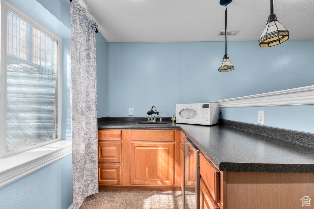 Bar with visible vents, wine cooler, a sink, hanging light fixtures, and white microwave