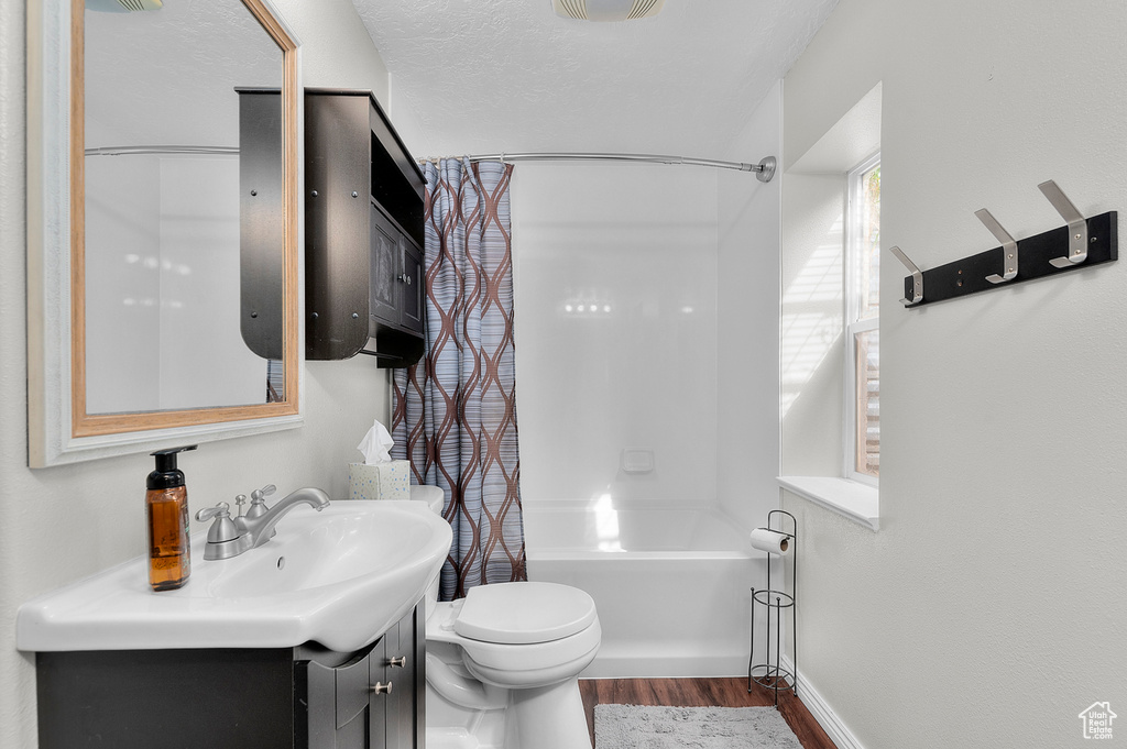 Full bath with toilet, wood finished floors, vanity, and shower / bathtub combination with curtain