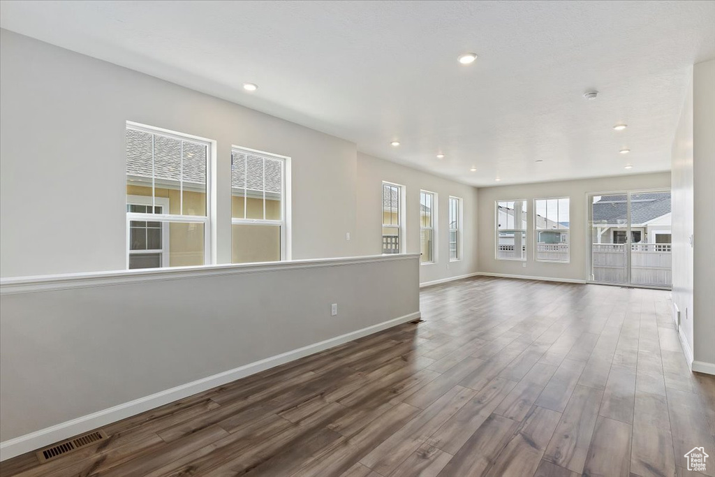 Unfurnished living room featuring wood finished floors, recessed lighting, baseboards, and visible vents