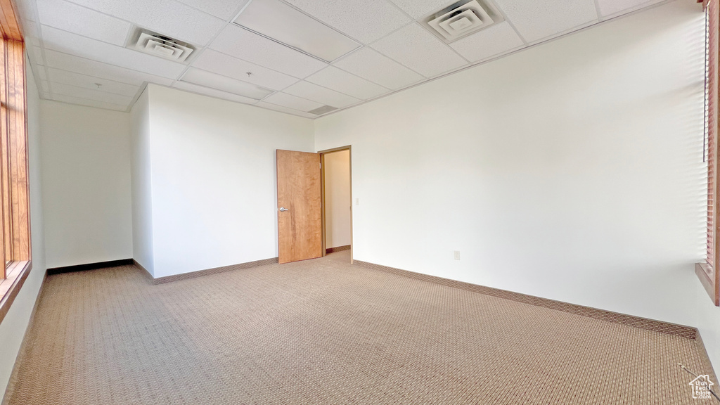 Spare room featuring a drop ceiling, carpet, baseboards, and visible vents