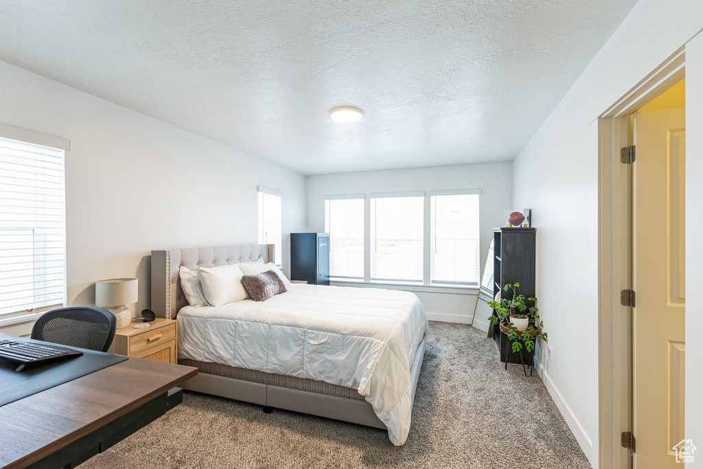 Bedroom featuring baseboards, a textured ceiling, and light colored carpet