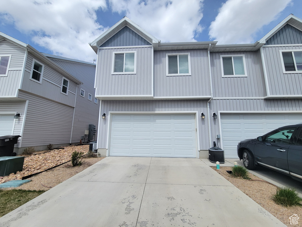 Multi unit property with board and batten siding, a garage, and driveway