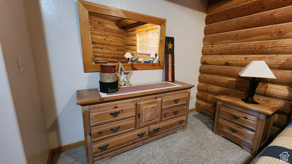 Bedroom with baseboards, log walls, and light colored carpet