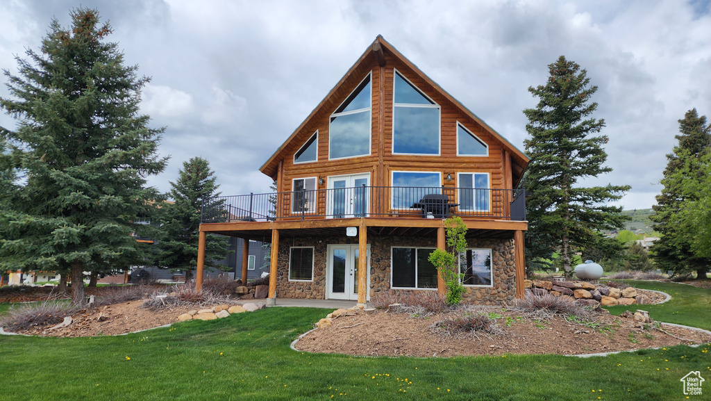 Rear view of property featuring stone siding, a yard, and a wooden deck