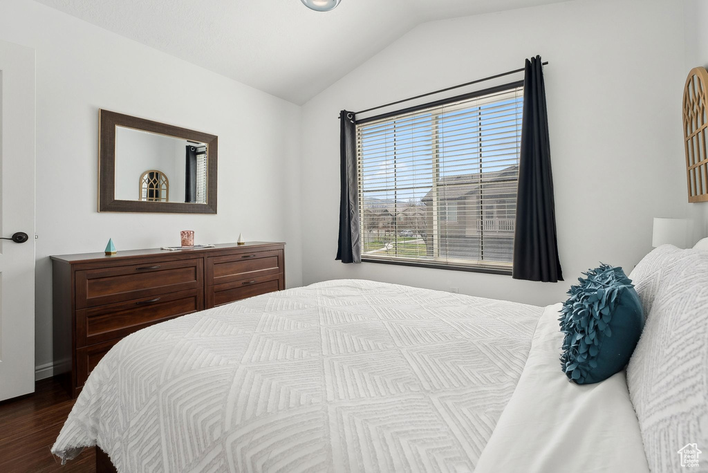 Bedroom with dark wood finished floors and lofted ceiling