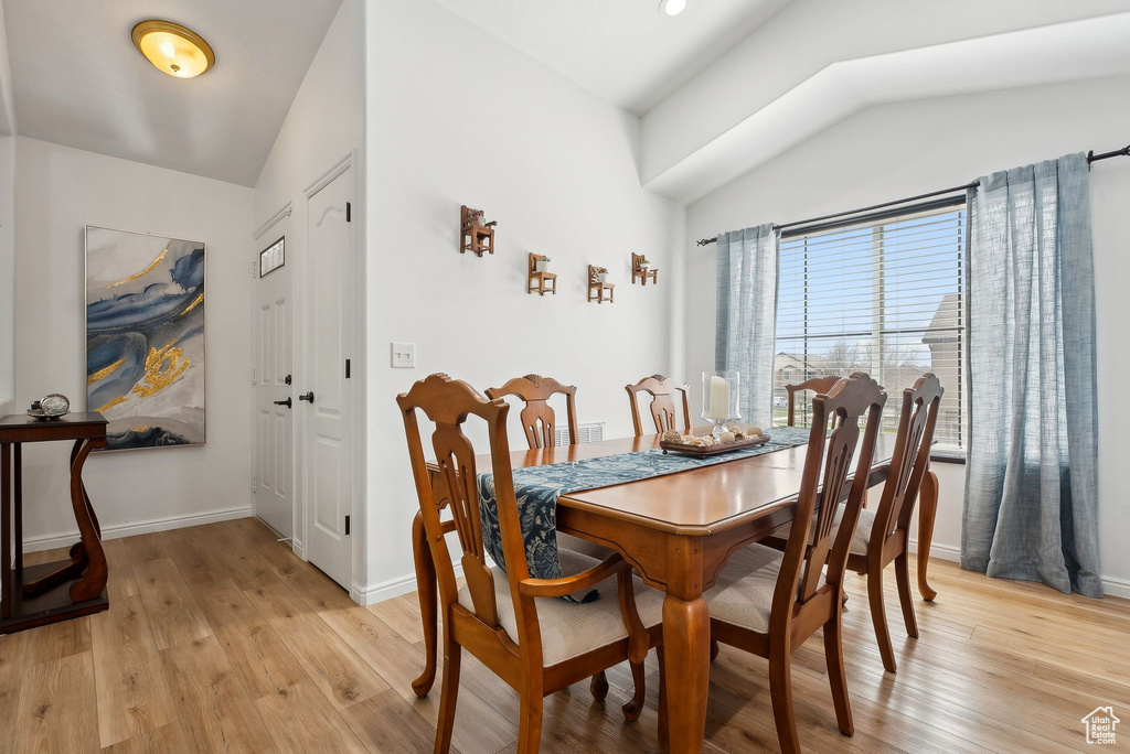 Dining space with baseboards, light wood-style floors, and lofted ceiling