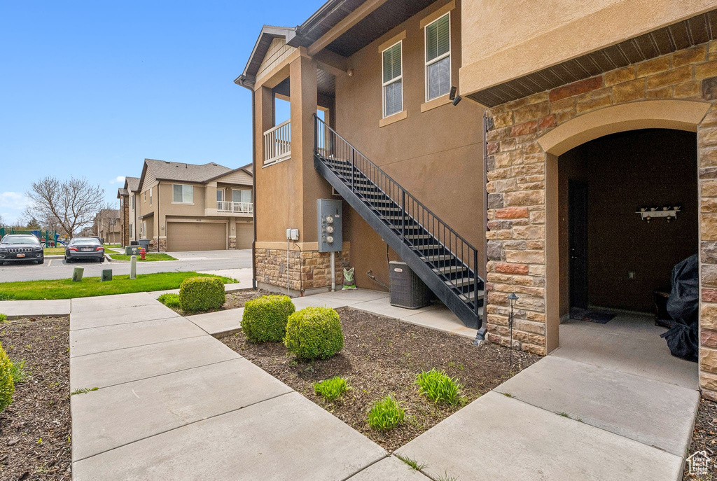 View of exterior entry featuring stone siding, a residential view, stucco siding, and central air condition unit