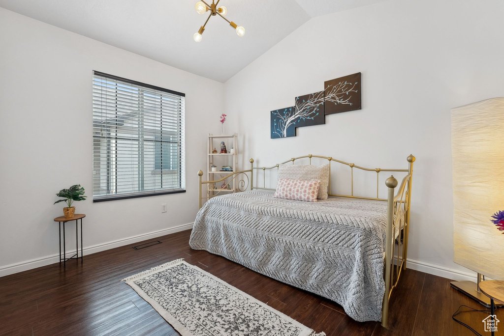 Bedroom with baseboards, vaulted ceiling, wood finished floors, and an inviting chandelier