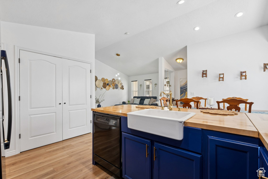Kitchen with a sink, wood counters, blue cabinetry, and black dishwasher