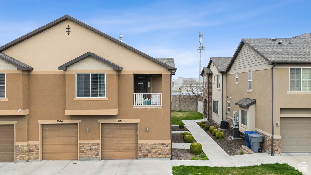Multi unit property with stone siding, stucco siding, and an attached garage