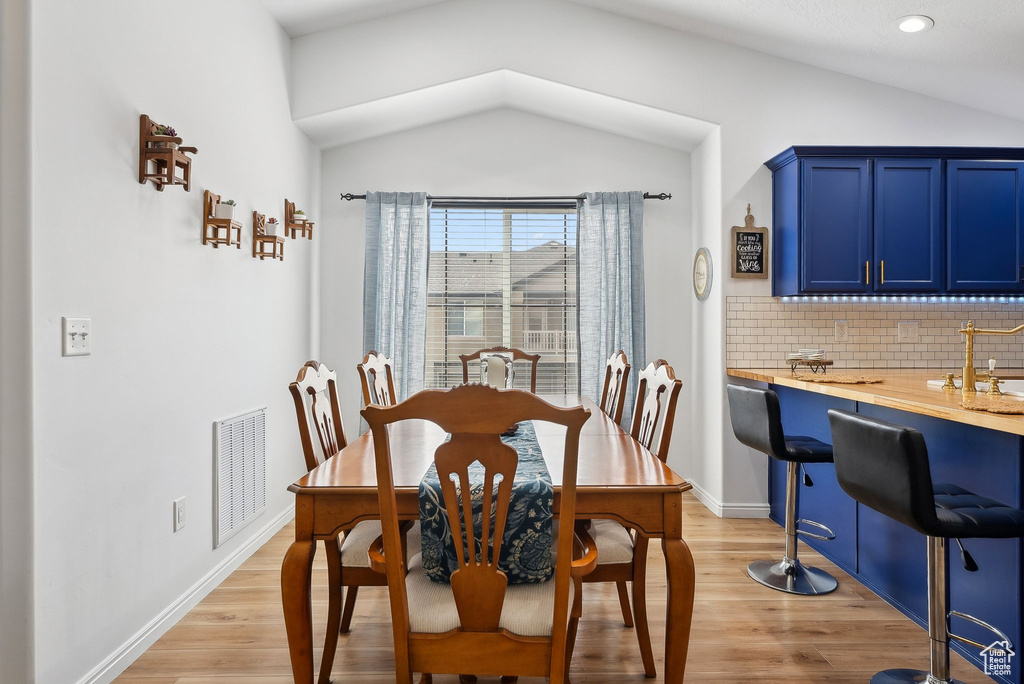 Dining area featuring light wood-type flooring, baseboards, lofted ceiling, and visible vents