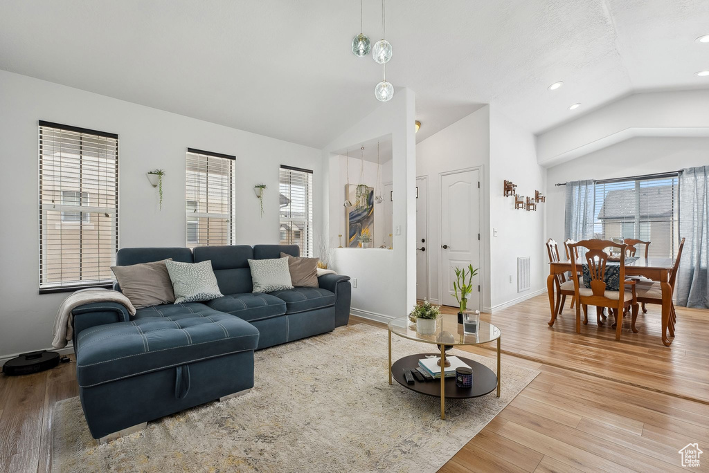Living area featuring baseboards, vaulted ceiling, recessed lighting, and light wood-type flooring