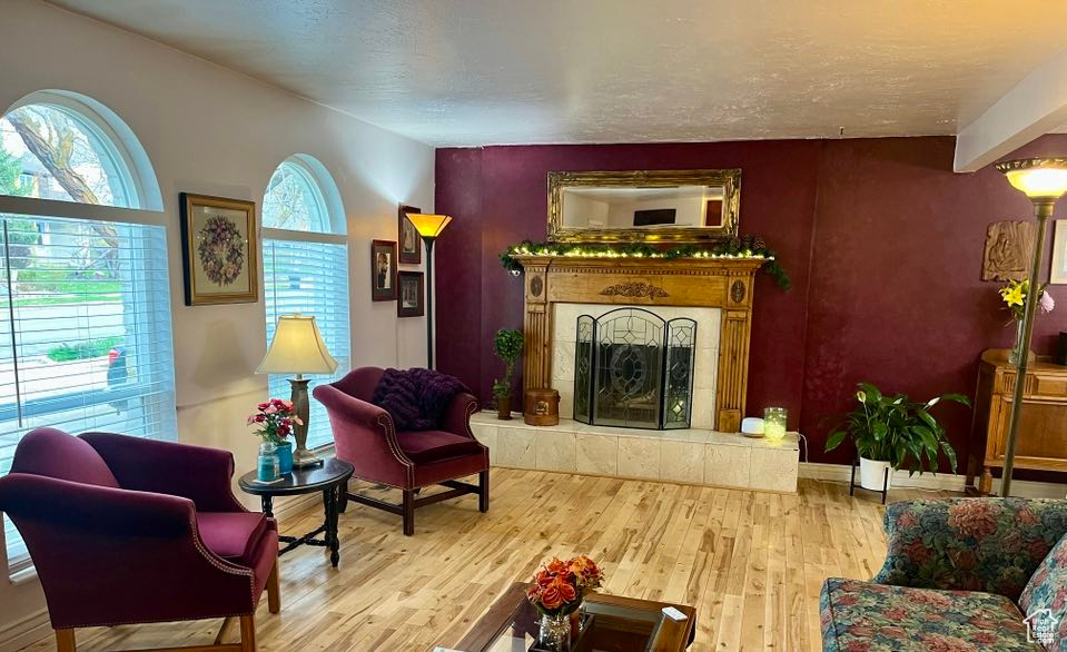 Living room with a textured ceiling, baseboards, a fireplace, and wood finished floors