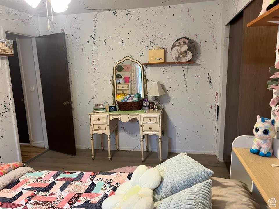 Bedroom featuring baseboards, wallpapered walls, and wood finished floors