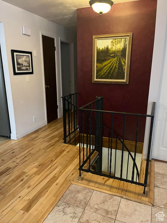 Staircase featuring baseboards, wood finished floors, and a textured ceiling