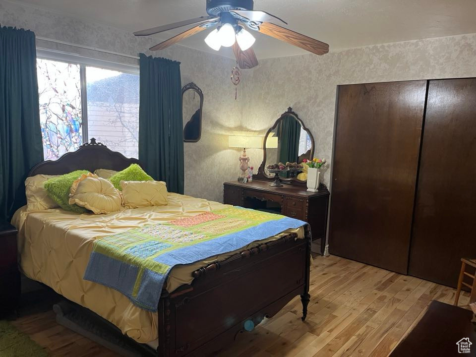 Bedroom featuring light wood-style flooring, wallpapered walls, and ceiling fan