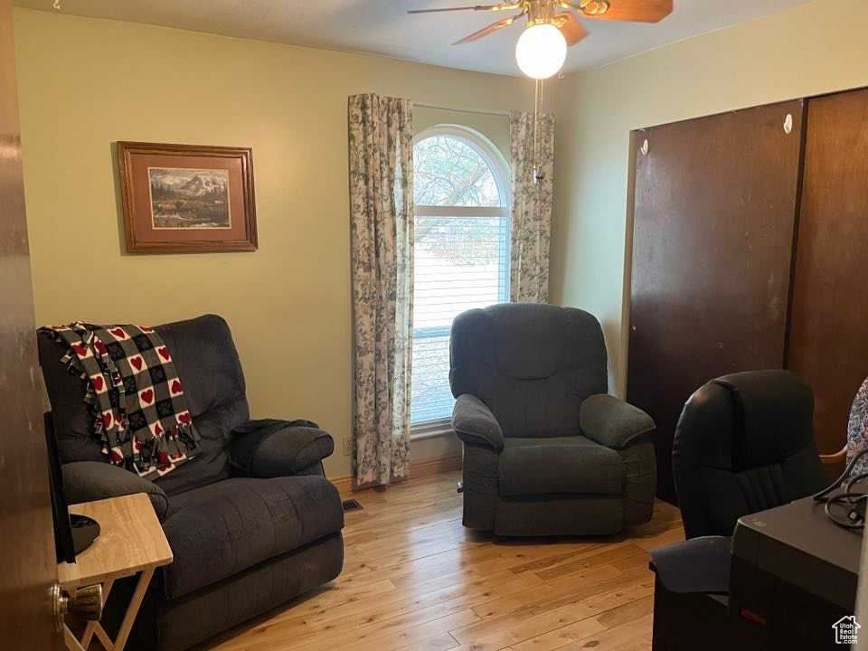 Sitting room featuring a ceiling fan, baseboards, and light wood-type flooring