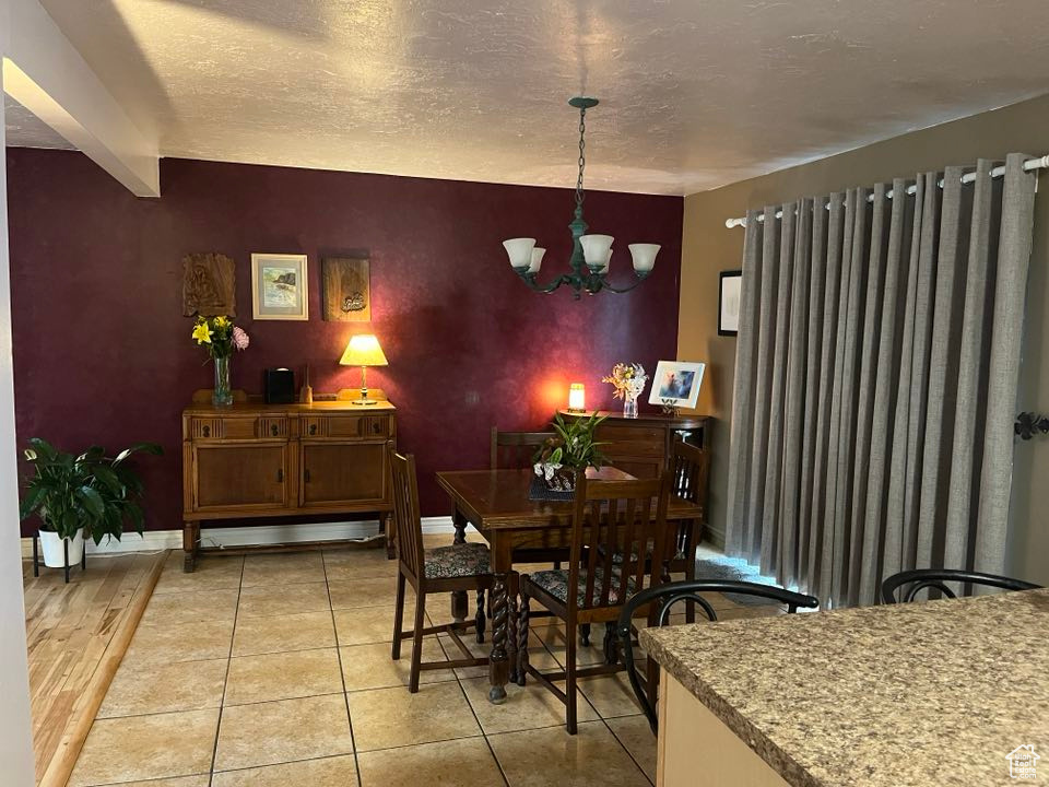 Dining room with an inviting chandelier, baseboards, an accent wall, and a textured ceiling