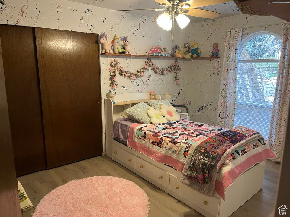 Bedroom featuring light wood finished floors, wallpapered walls, and ceiling fan