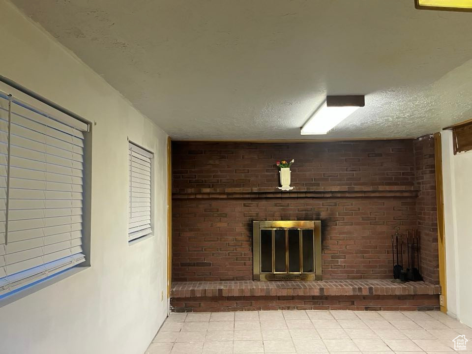 Unfurnished living room featuring a textured ceiling and a brick fireplace