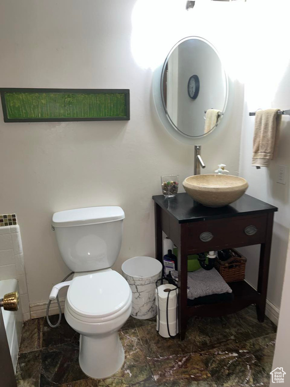 Bathroom with toilet, vanity, radiator, and baseboards