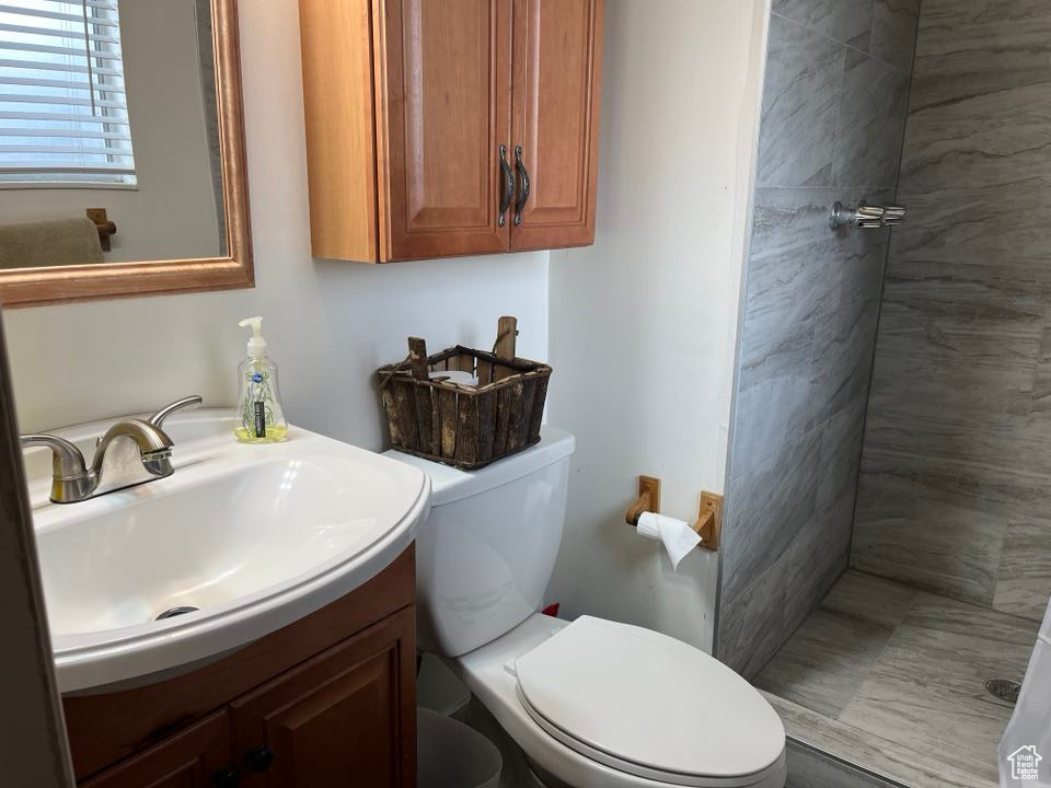 Bathroom with toilet, tiled shower, and vanity