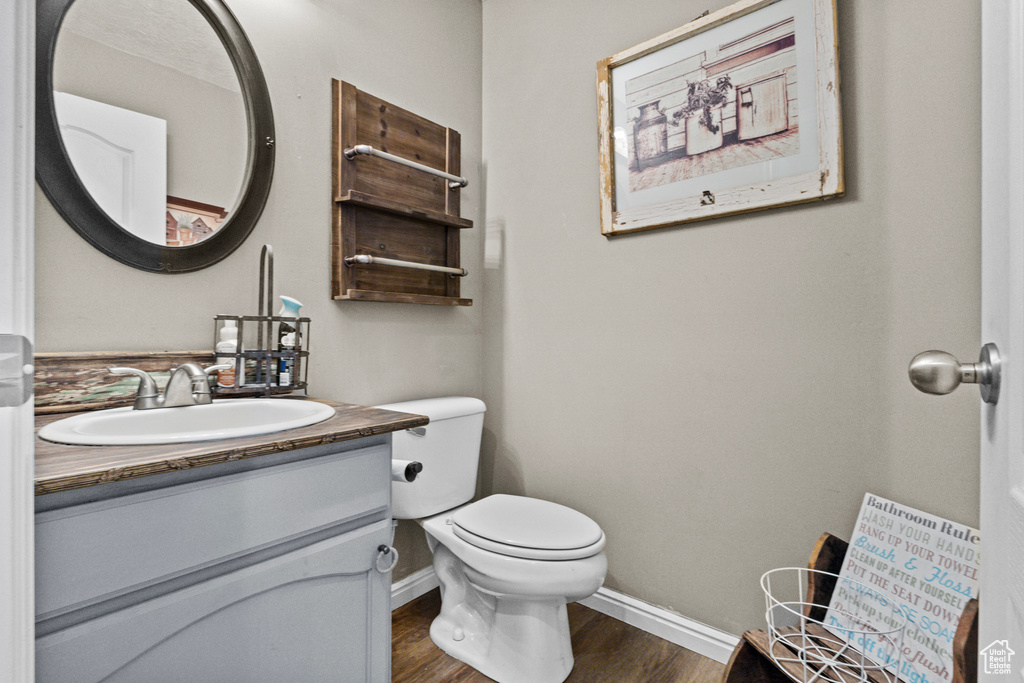 Bathroom with baseboards, toilet, wood finished floors, and vanity