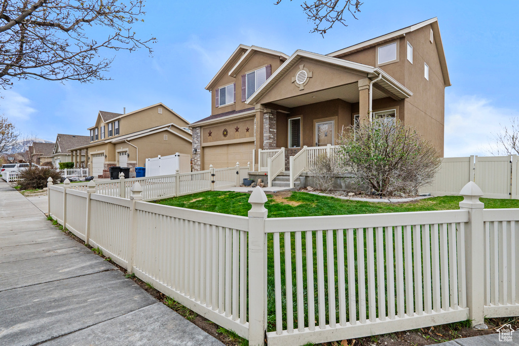 View of front of home with a front lawn, a fenced front yard, a gate, and stucco siding