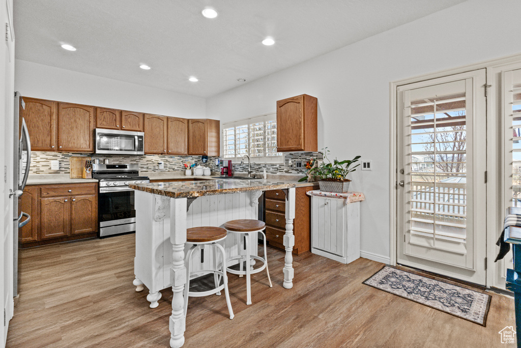 Kitchen featuring light wood-style flooring, a sink, stainless steel appliances, and brown cabinetry