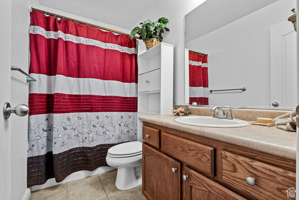 Bathroom with tile patterned floors, vanity, toilet, and a shower with shower curtain