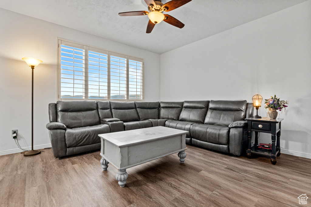 Living room featuring a ceiling fan, baseboards, and wood finished floors